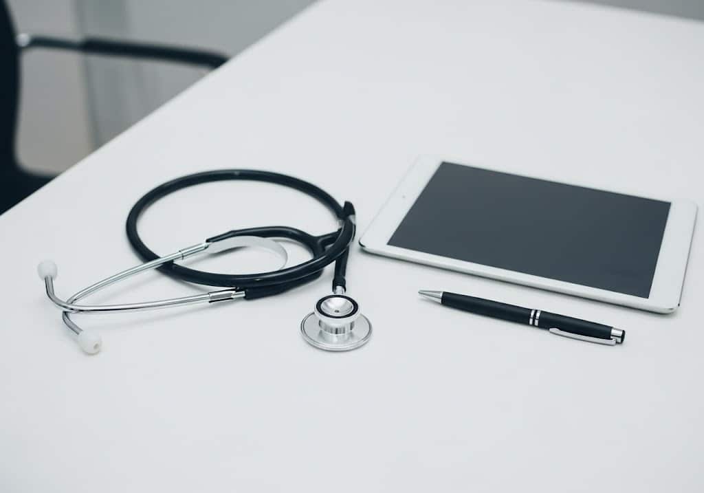 stethoscope, tablet, and pen on table