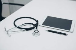stethoscope, tablet, and pen on table